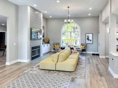 A living room with a yellow couch and a fireplace.