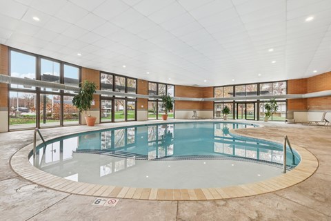A round indoor swimming pool with a glass barrier.