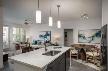 A kitchen with a marble countertop and a dining table with chairs.