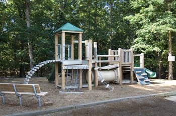A playground with a wooden structure and a green roof.