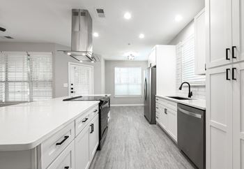 A modern kitchen with white cabinets and stainless steel appliances.