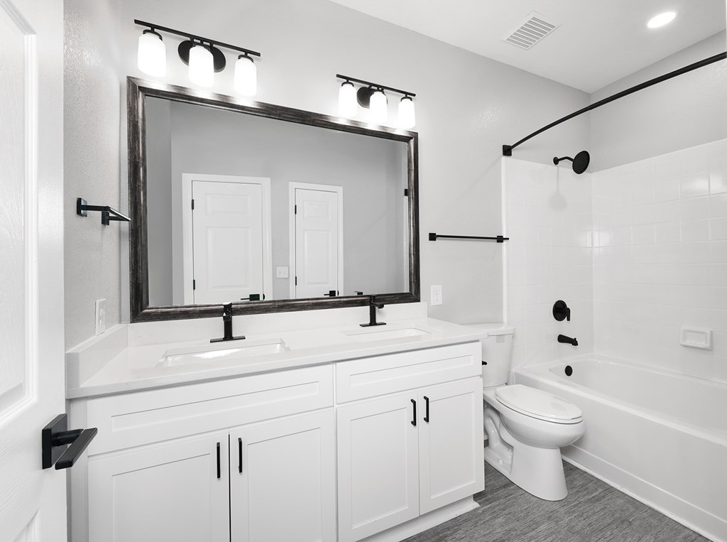 Bathrooms with quartz countertops, dual vanities and framed mirrors