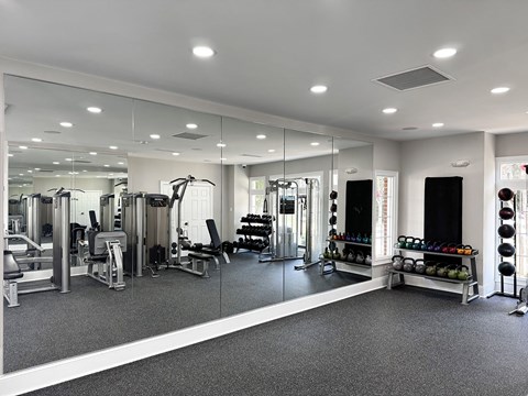A spacious gym with a variety of equipment and a mirrored wall.