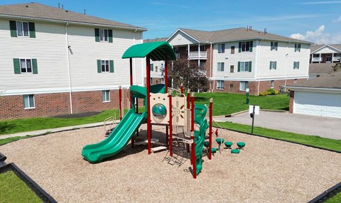 A playground with a green slide and red and green play structure.