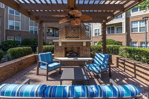 A patio with a fireplace and chairs.