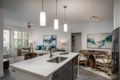 A modern kitchen with a marble countertop and a dining area with a wooden table and chairs.