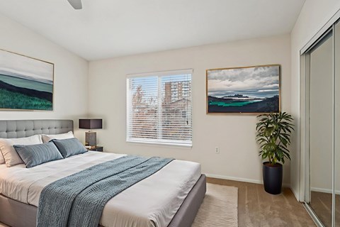 A bedroom with a large bed and a painting on the wall.