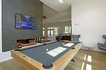 A pool table with a television screen showing a news channel in the background.
