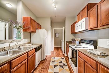 A kitchen with wooden cabinets and a checkered floor mat.