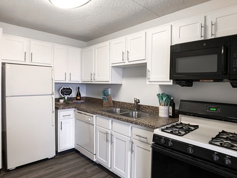 A kitchen with white cabinets and a black microwave above the stove.