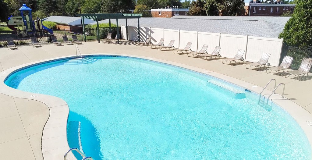 A large swimming pool with a white fence around it.