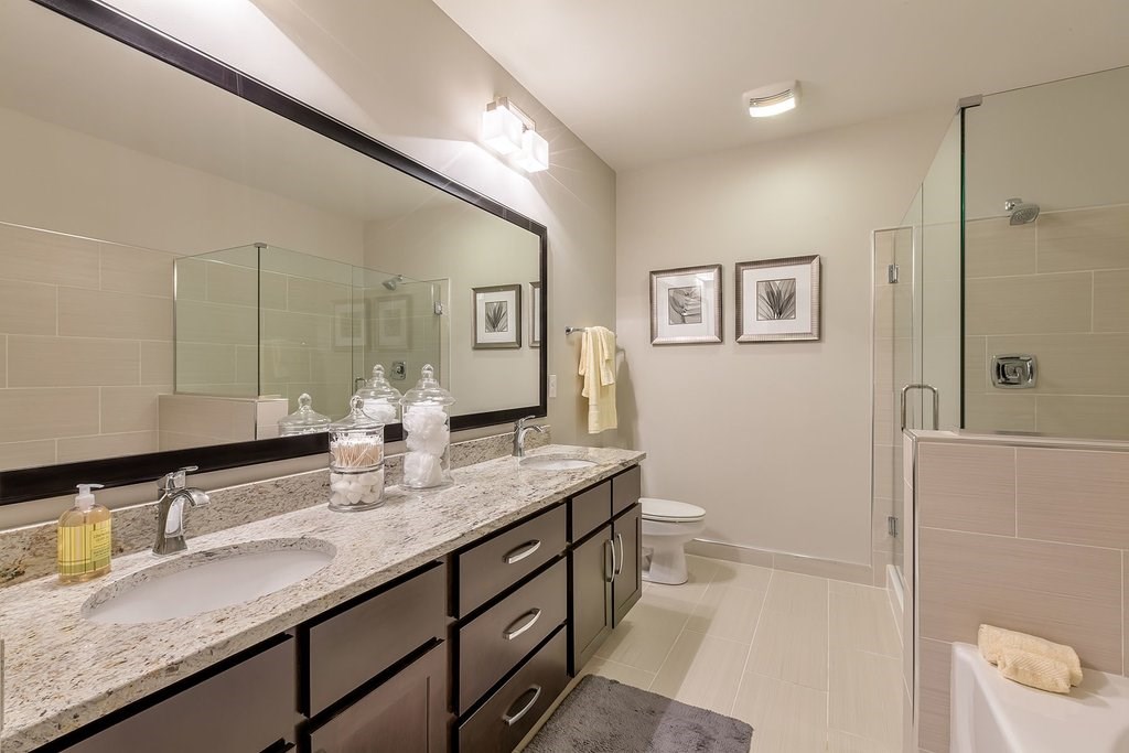 Bathrooms with dual vanities, framed mirrors and granite countertops