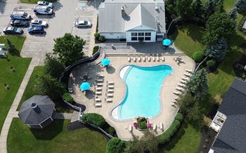 An aerial view of a swimming pool surrounded by lawn chairs and umbrellas.