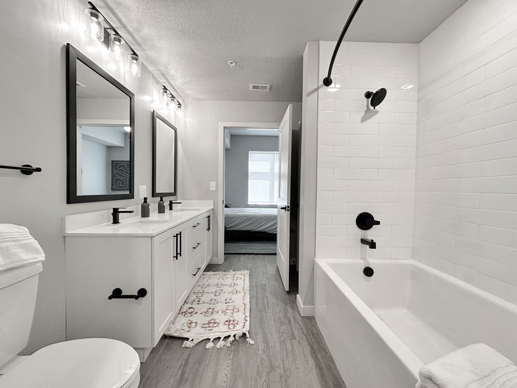 Dual vanities, garden soaking tub with curved shower rods and framed mirrors in bathrooms