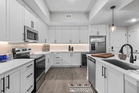 A modern kitchen with white cabinets and stainless steel appliances.