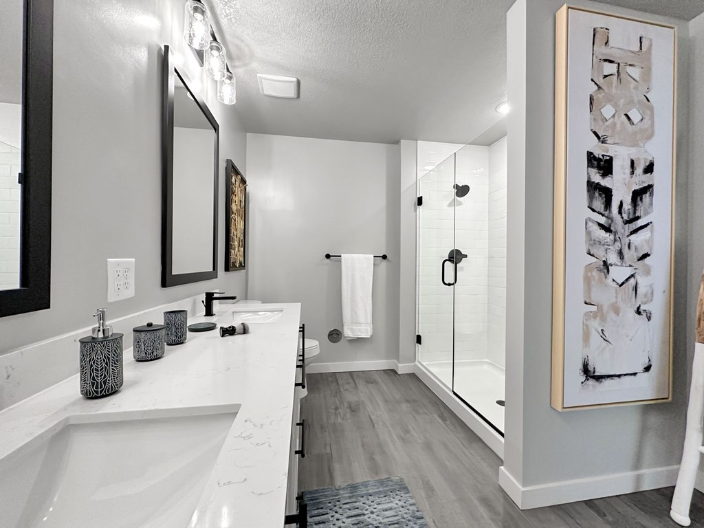 Main bathroom in model with dual vanities and frameless walk-in shower