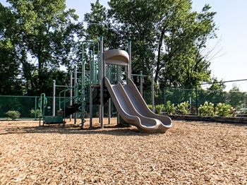 A playground with a slide and a green fence.