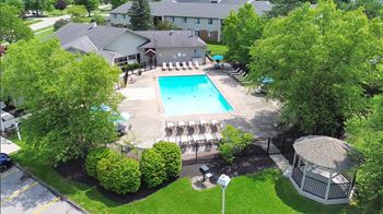 A pool surrounded by trees and a gazebo.