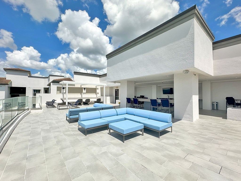 Partially shaded rooftop terrace with TVs, kitchen and bar