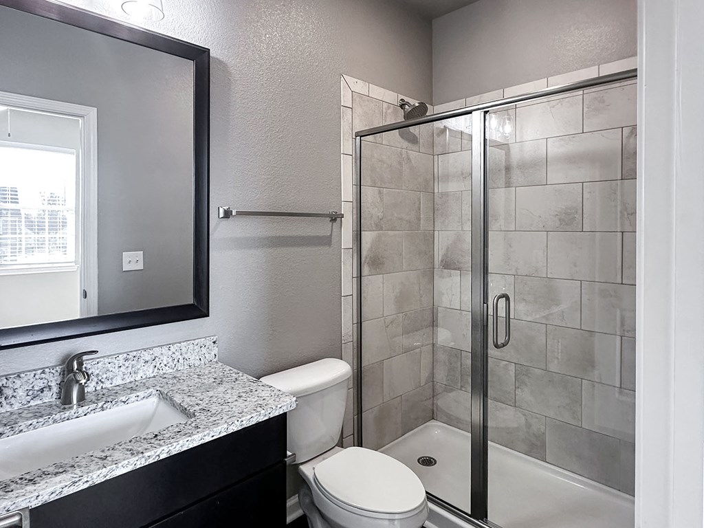 Townhome bathroom with granite countertops, framed mirror and shower