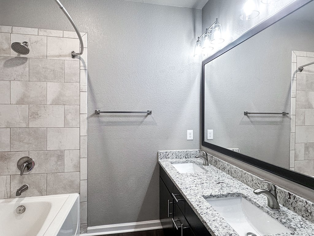 Townhome bathroom with granite countertops, dual vanities and framed mirror