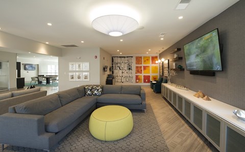 A modern living room with a grey sofa and a yellow ottoman.