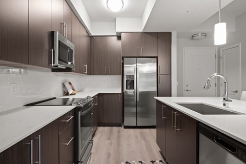 A modern kitchen with dark wood cabinets and stainless steel appliances.