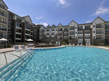 A large swimming pool in front of apartment buildings.