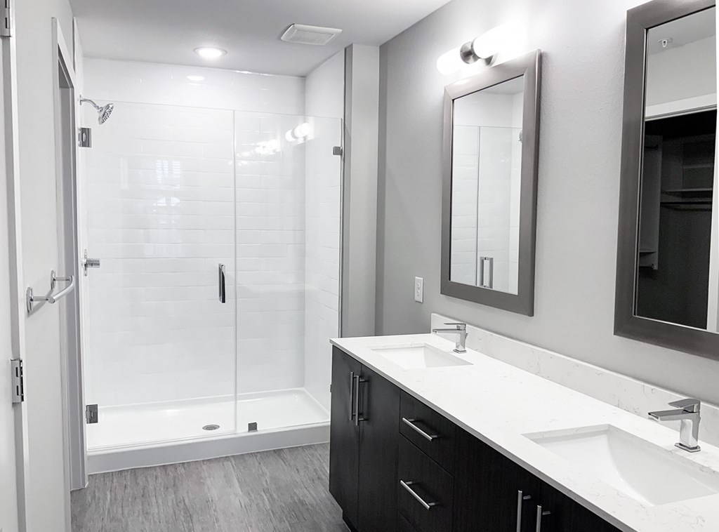 Frameless walk-in showers, dual vanities and framed mirrors in bathrooms