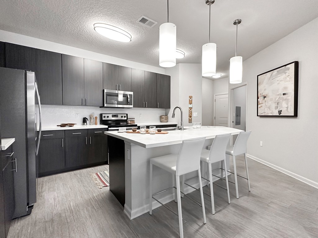 Fully-equipped kitchens with quartz countertops, stainless steel appliances, and overhead designer light fixtures