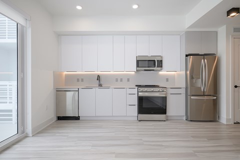 A modern kitchen with white cabinets and stainless steel appliances.