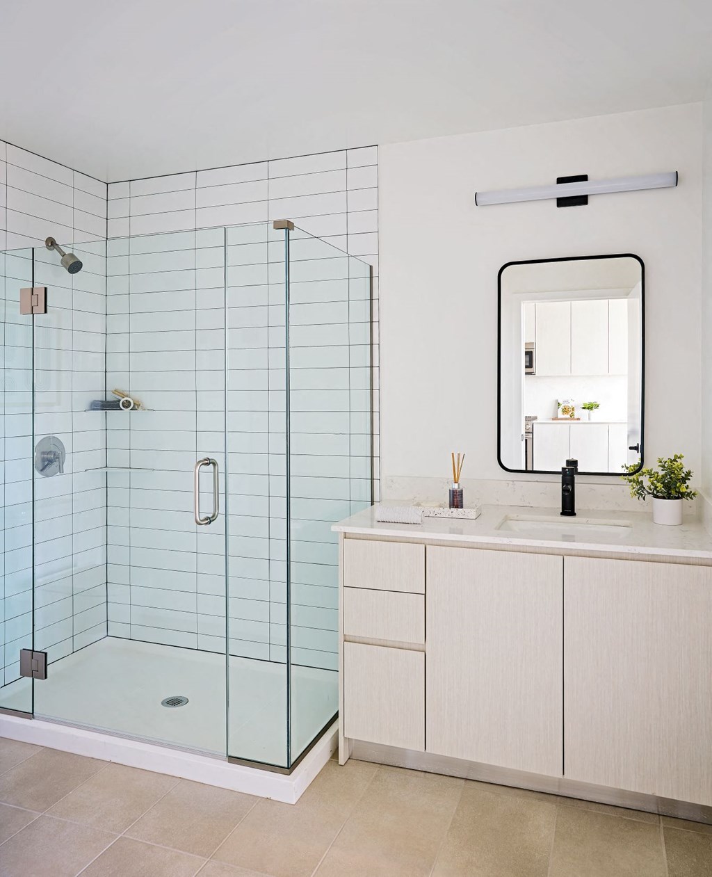 A modern bathroom with a glass shower and white cabinetry.