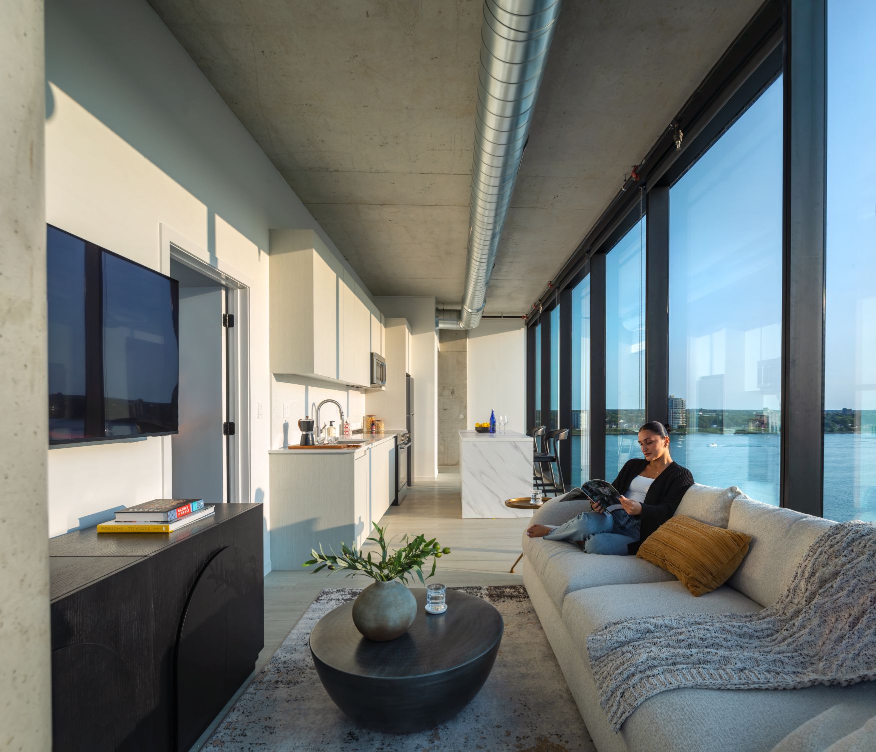 A woman is sitting on a couch in a modern living room.