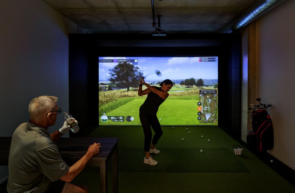 A man is playing a golf game on a screen in a room.