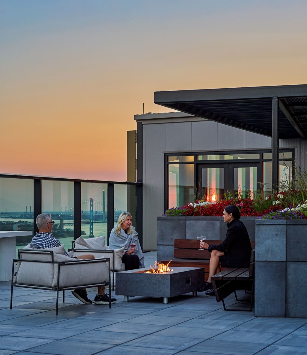 Three people are sitting on a patio with a view of the city.