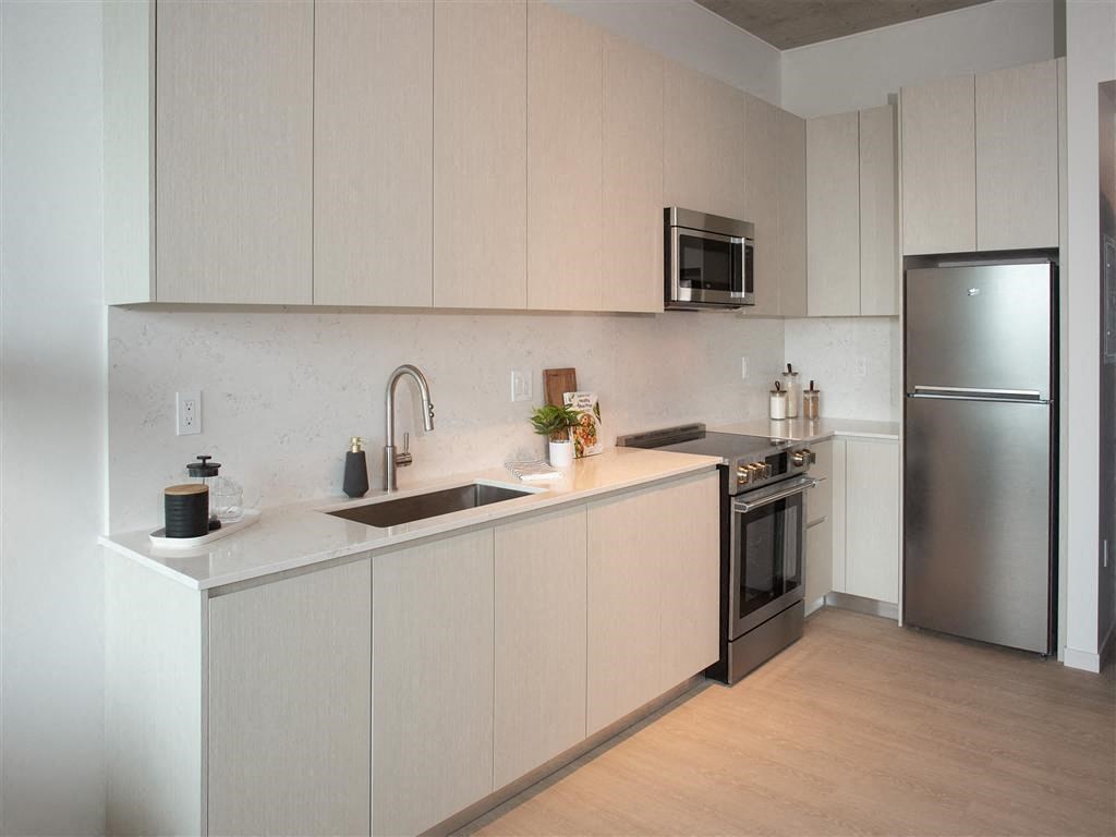 A modern kitchen with a sink, stove, and refrigerator.