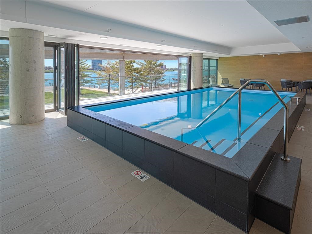 A rectangular indoor swimming pool with a glass barrier.