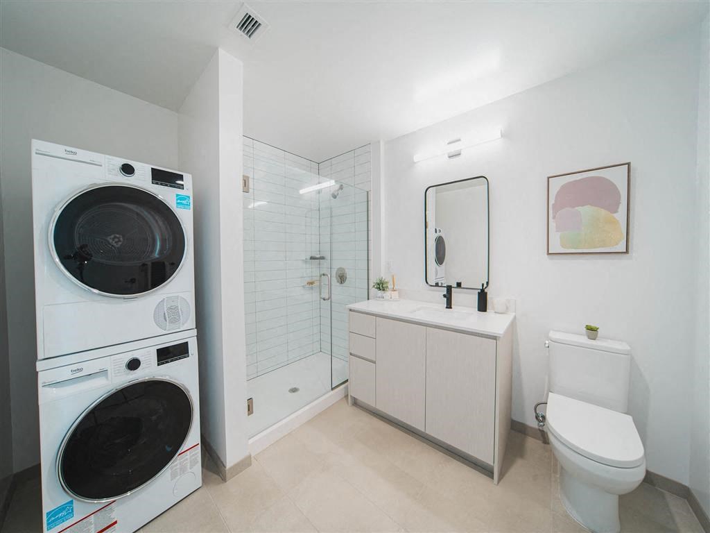 A white bathroom with a washer and dryer built in.