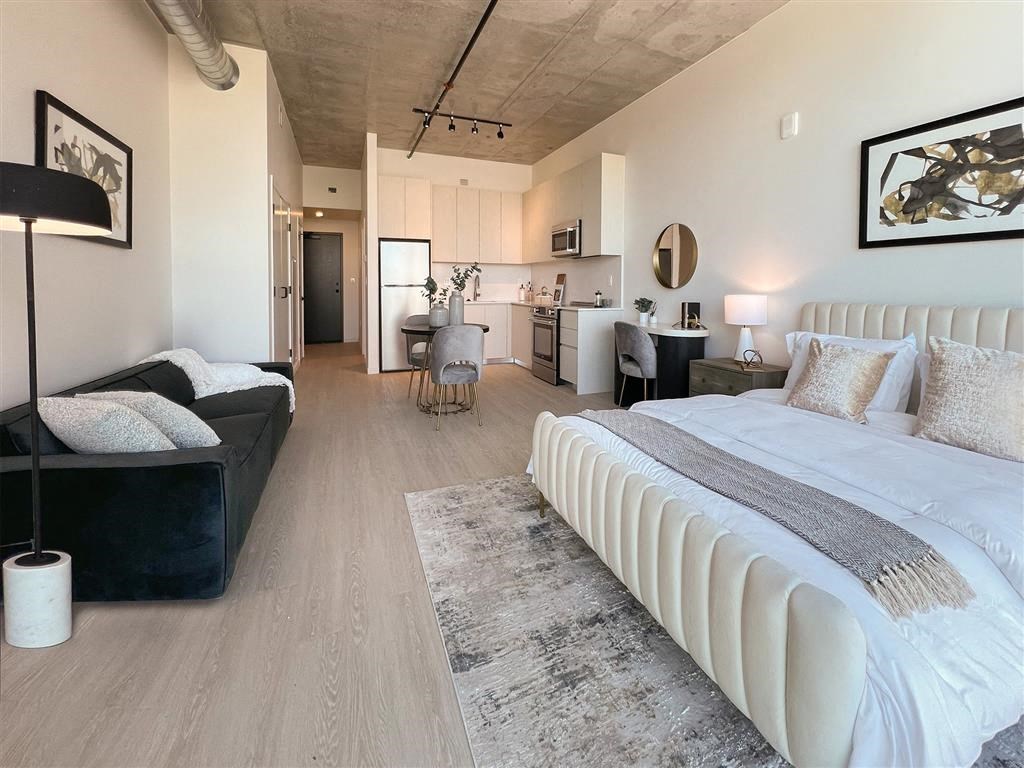 A modern bedroom with a large bed and a black floor lamp.