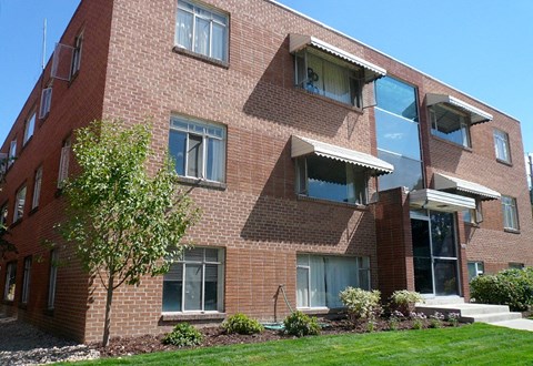 A red brick building with a tree in front.