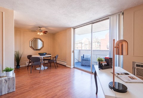 A dining room with a table set for four and a view of the city outside the window.