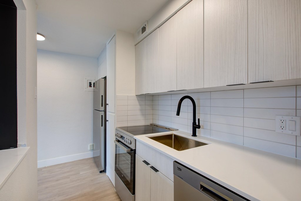 A kitchen with white cabinets and a black faucet.