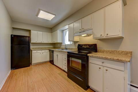 A kitchen with white cabinets and a black fridge.