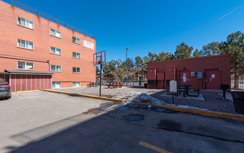 A basketball hoop is attached to a building with a red brick exterior.