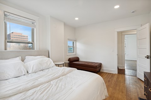 A bedroom with a large bed and a window overlooking a building.