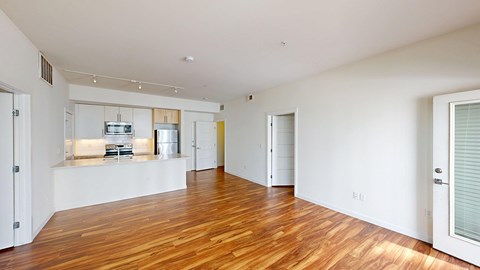 A spacious room with wooden floors and white walls.