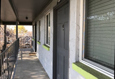 A porch with a black door and green trim.