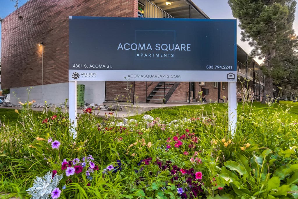 A sign for Acoma Square Apartments is in front of a building.