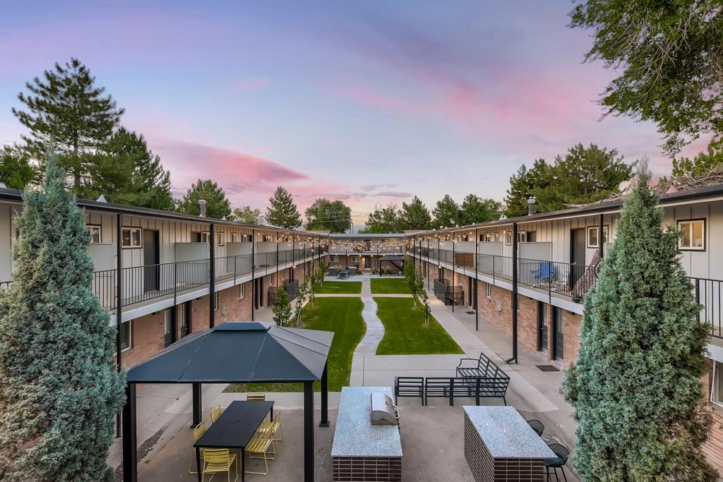 A sunset view of a courtyard with a picnic table and chairs.