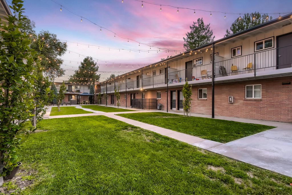 A sunset view of a residential area with apartment buildings and green lawns.